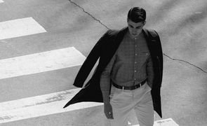 homem vestido de social atravessando faixa de pedestre