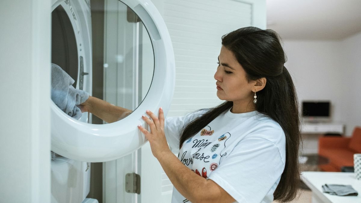 mulher colocando roupa em maquina