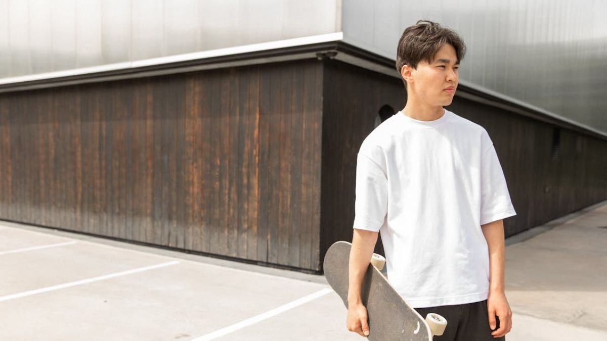 homem de camisa oversized branca com skate na mao